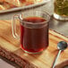 A glass mug of Folgers Classic Roast coffee on a wooden board with a spoon.