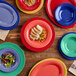 A stack of yellow Acopa Foundations melamine plates on a table with food.