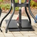 A person using a metal pole to adjust a Lancaster Table & Seating stack plate on a table outdoors.