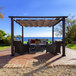 A patio with a Paragon Outdoor Modena aluminum pergola over a table and chairs.