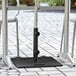 A black Lancaster Table & Seating umbrella base on a brick patio.