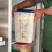 A man holding a Cambro CamSquares container full of apples.