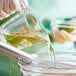 A person pouring Mazola Vegetable Plus! Oil into a measuring cup.