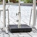 A Lancaster Table & Seating black metal umbrella base on a black surface.