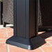 A black metal post of a Paragon Outdoor Santa Monica Hard Top Gazebo on a brick surface.