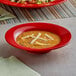 A red bowl of soup with crackers on a table in a Mexican restaurant.