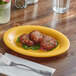 An Acopa yellow melamine platter with food on it.