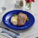 An Acopa Foundations blue melamine plate with a piece of meat and rice on it, with a glass of water on the table.