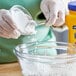 A person pouring Argo Corn Starch into a glass bowl.