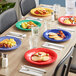 A table with yellow, blue, and white Acopa Foundations melamine plates of food and glasses of water.