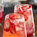 Two glasses of red strawberry drinks with ice and garnish, each garnished with freeze-dried strawberry slices.