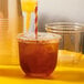 A Tossware natural plant-based plastic flat lid on a plastic cup with a straw.