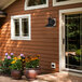 An outdoor house with a Globe oil rubbed bronze wall sconce on the front porch and yellow flowers in a pot.