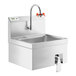 A stainless steel Regency wall mounted sink with a faucet and a knee-operated valve.