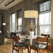 A restaurant dining room with a table and Globe Modern Farmhouse Matte Black / Beige Fabric Chandelier above it.