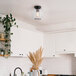 A kitchen with white cabinets and a Globe matte black flush mount light.