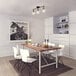 A white dining table and chairs in a restaurant dining area with a Globe matte black island light with brass accents.