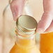 A person opening a Gold Metal Lid on a bottle of liquid.