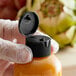 A hand holding a plastic bottle with a black flip top lid.