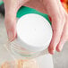 A hand holding a plastic container with a 63/400 white ribbed plastic cap on it.