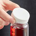 A hand holding a bottle of red liquid with a white plastic 38/400 continuous thread cap.