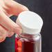 A hand holding a bottle of red liquid with a white plastic 38/400 Continuous Thread Cap.