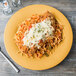 A Diamond Mardi Gras melamine plate with a plate of spaghetti with meat and cheese on top on a table.