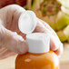 A hand in a glove opening a plastic bottle of liquid using a 28/410 white unlined flip top lid.