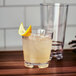 A Tossware Reserve Tritan plastic rocks glass filled with lemonade and a lemon wedge.