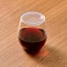 A Tossware large plastic lid with straw slot on a glass of brown liquid on a table.