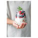 A hand holding a Tossware plastic wine glass filled with fruit.