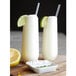 Two Tossware plastic champagne flutes filled with lemonade and garnished with lime slices and straws.