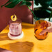 A hand holding a Tossware Reserve Go-To Blush Tritan plastic rocks glass of liquid with a lemon slice.