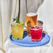 A tray of Tossware Reserve plastic double old fashioned glasses filled with ice and drinks.