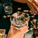 A person holding a Tossware Tritan plastic stemless martini glass with olives in it.
