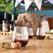 A Tossware plastic wine glass filled with wine on a table.