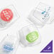 A set of four customizable clear plastic vino glasses, each with a different printed logo or design.