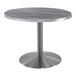 A Holland Bar Stool round table with a stainless steel base and greystone top.