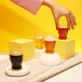 A person holding a Tossware plastic mini pint glass of beer.