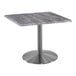 A Holland Bar Stool EnduroTop square table with a stainless steel base and a gray top.