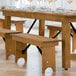 A Lancaster Table & Seating Vineyard Series wooden folding bench on a wood floor.