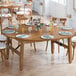 A Lancaster Table & Seating Vineyard Series round brown folding table set for dinner with plates and glasses.