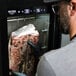 A man holding a piece of meat in a Pro Smoker TR-50 Reserve dry aging cabinet.