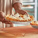 A person holding a medium depth pie in a Baker's Lane foil pan.