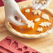 A red Wilton silicone mold for pie crusts with leaves and leaves on it.