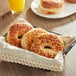 Just Bagels Asiago bagels in a basket on a table with orange juice.