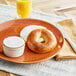 A Just Bagels sundried tomato bagel with cream cheese on a white plate.