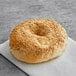 A Just Bagels sesame bagel with sesame seeds on it.