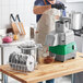 A man in an apron using an AvaMix commercial food processor to cut food in a kitchen.