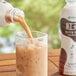 A bottle of Ito En Black Iced Tea with Milk being poured into a glass of brown liquid.